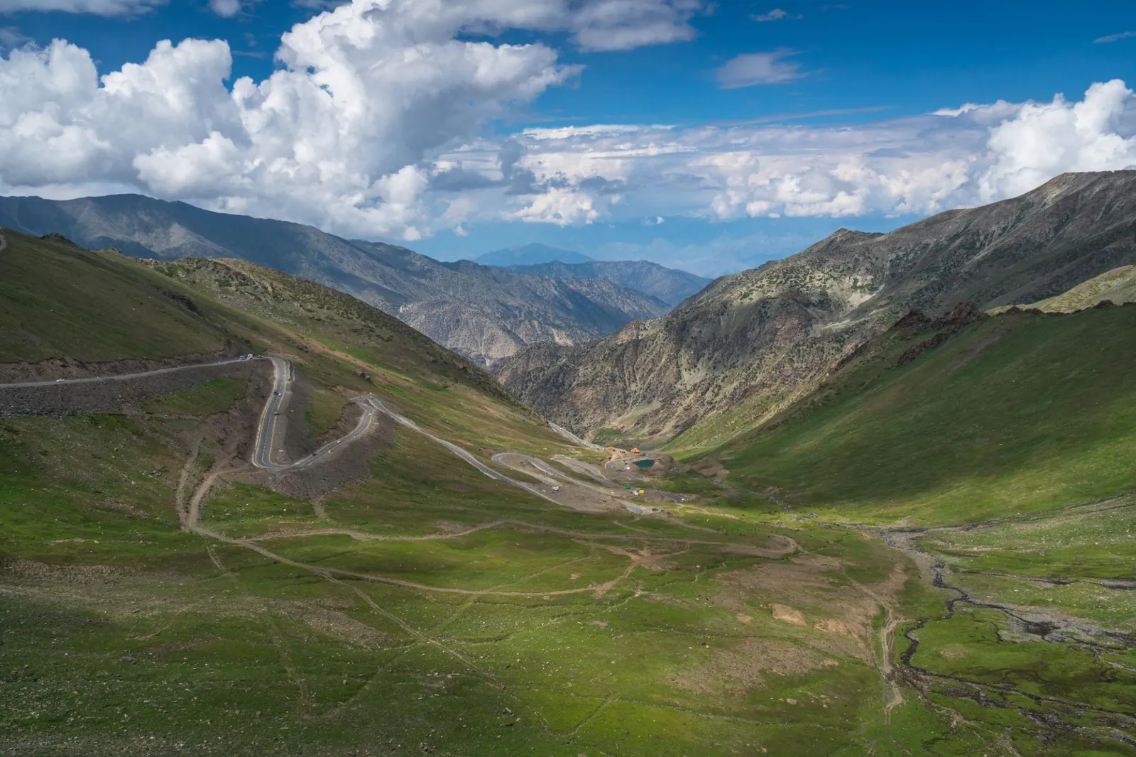 A road winding up green slopes to Babusar Pass