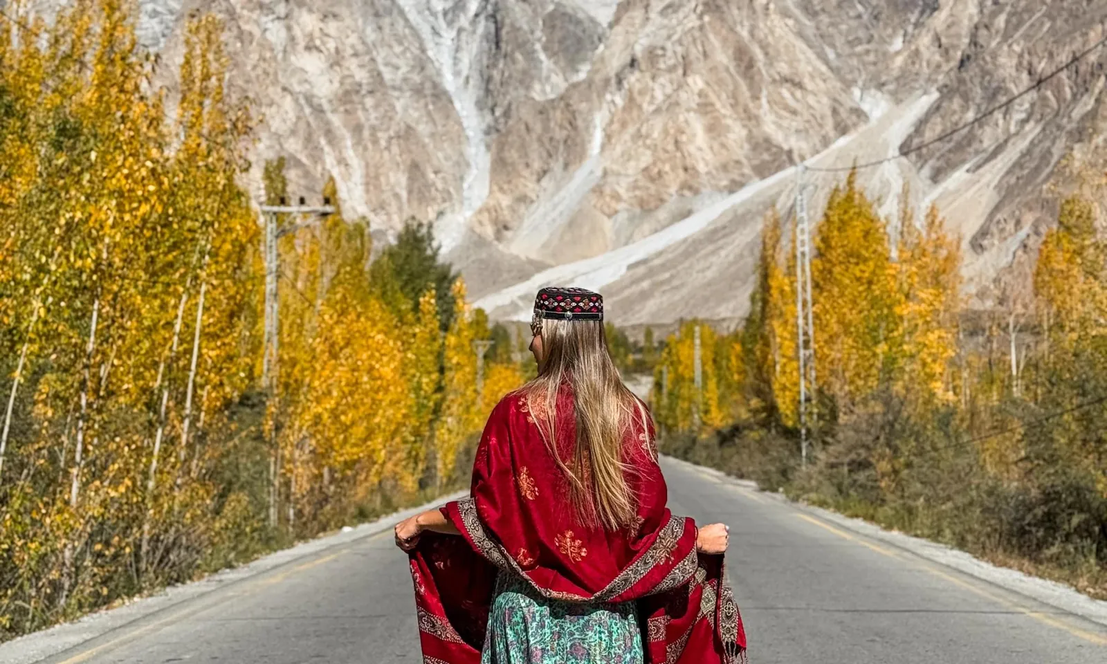 A traveller on a mountain road lined with autumn trees